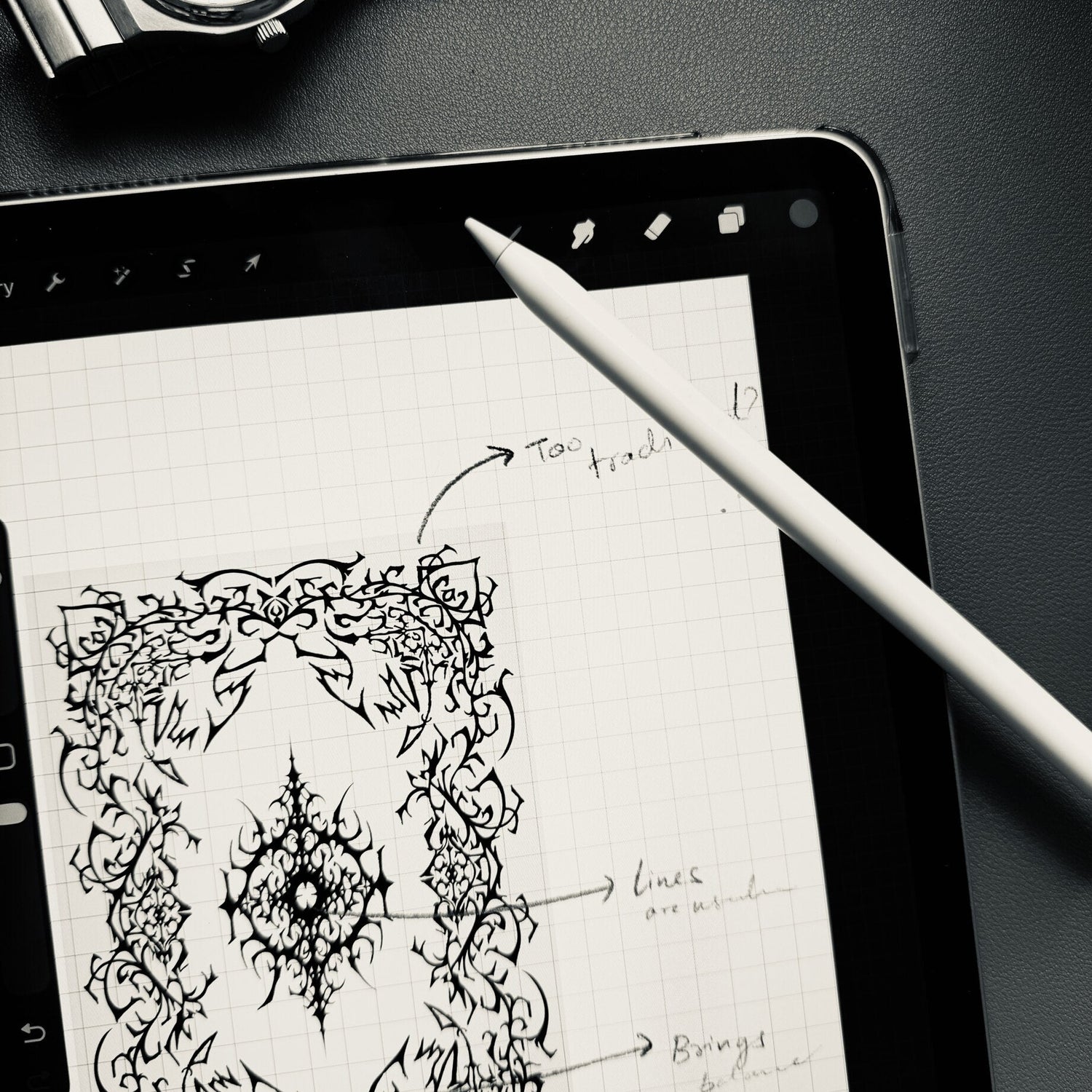 Tablet with artistic design on a dark surface with a watch and pencil.